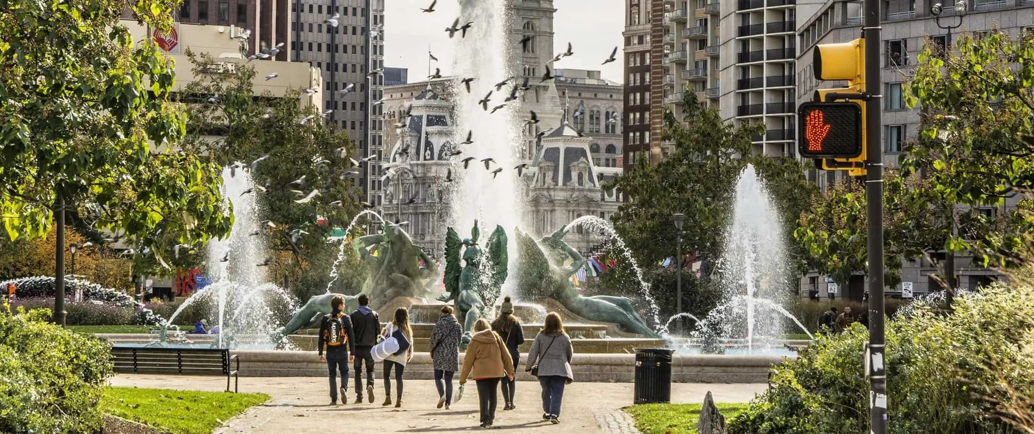 Pessoas andando em um parque urbano em frente a uma fonte na Filadélfia, EUA