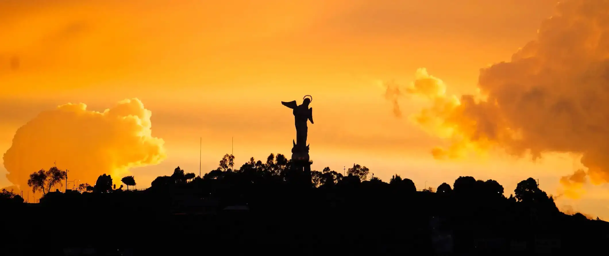 Una estatua en una colina recortada durante una brillante puesta de sol naranja