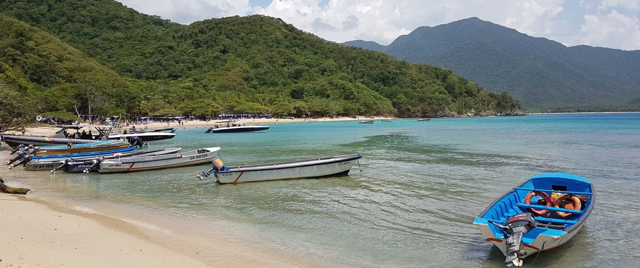 Små båter stoppet på en strand i Parque Tayrona, en nasjonalpark i Colombia