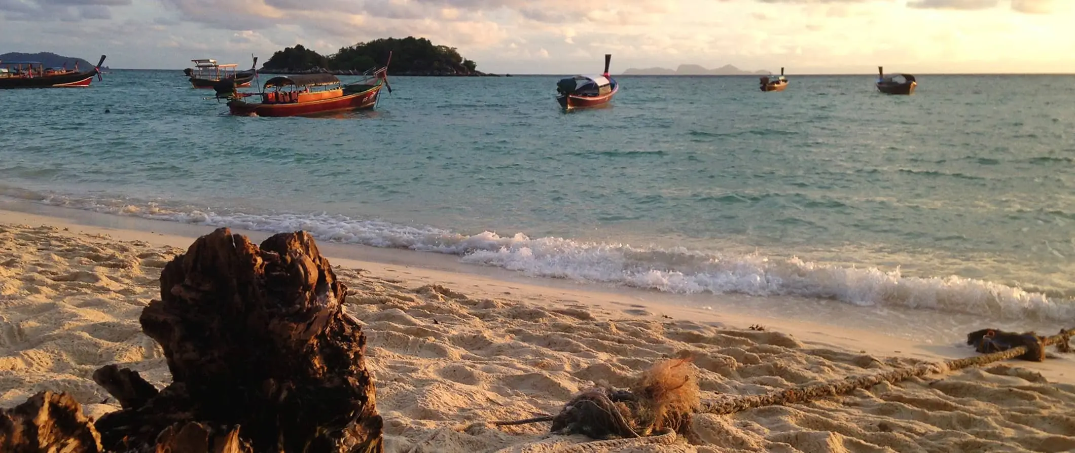 En tom strand i Ko Lipe, Thailand med små båtar förankrade utanför kusten