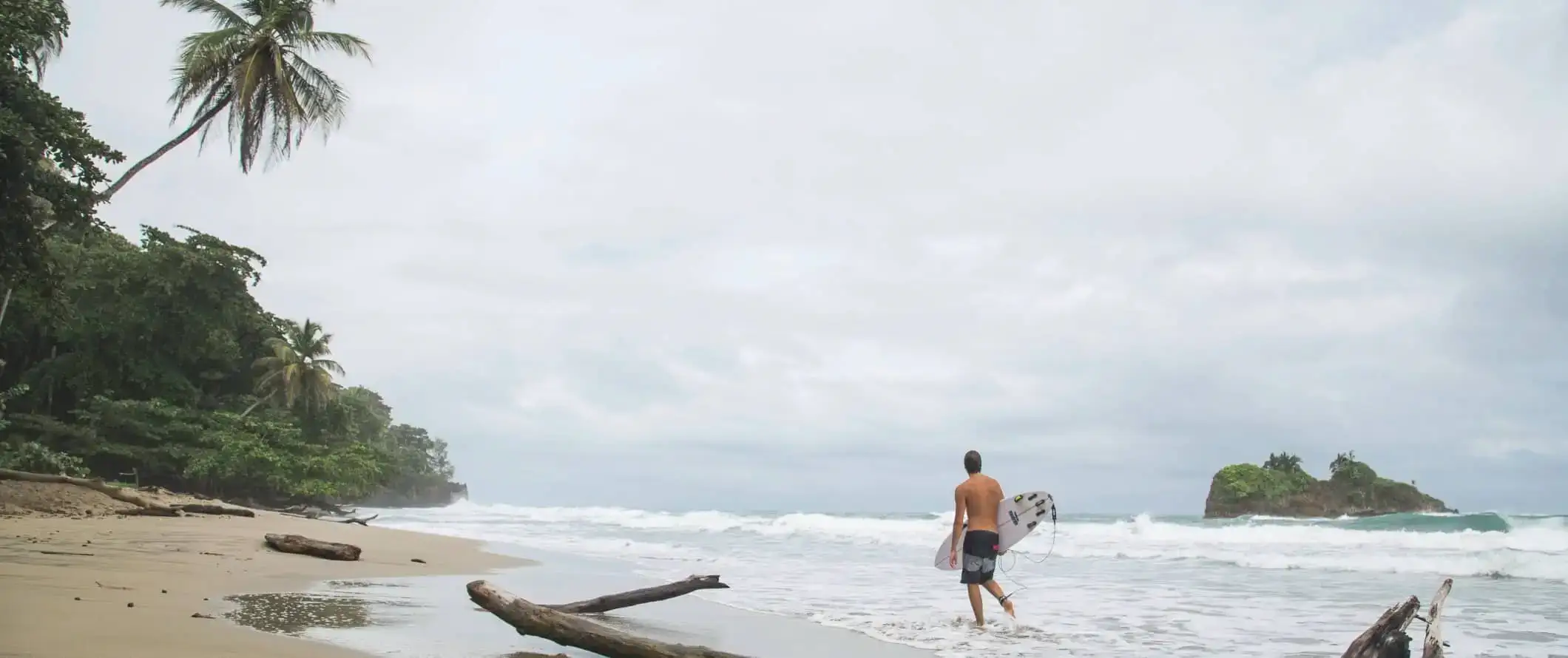 Persona caminant per la platja amb una taula de surf a Puerto Viejo, Costa Rica