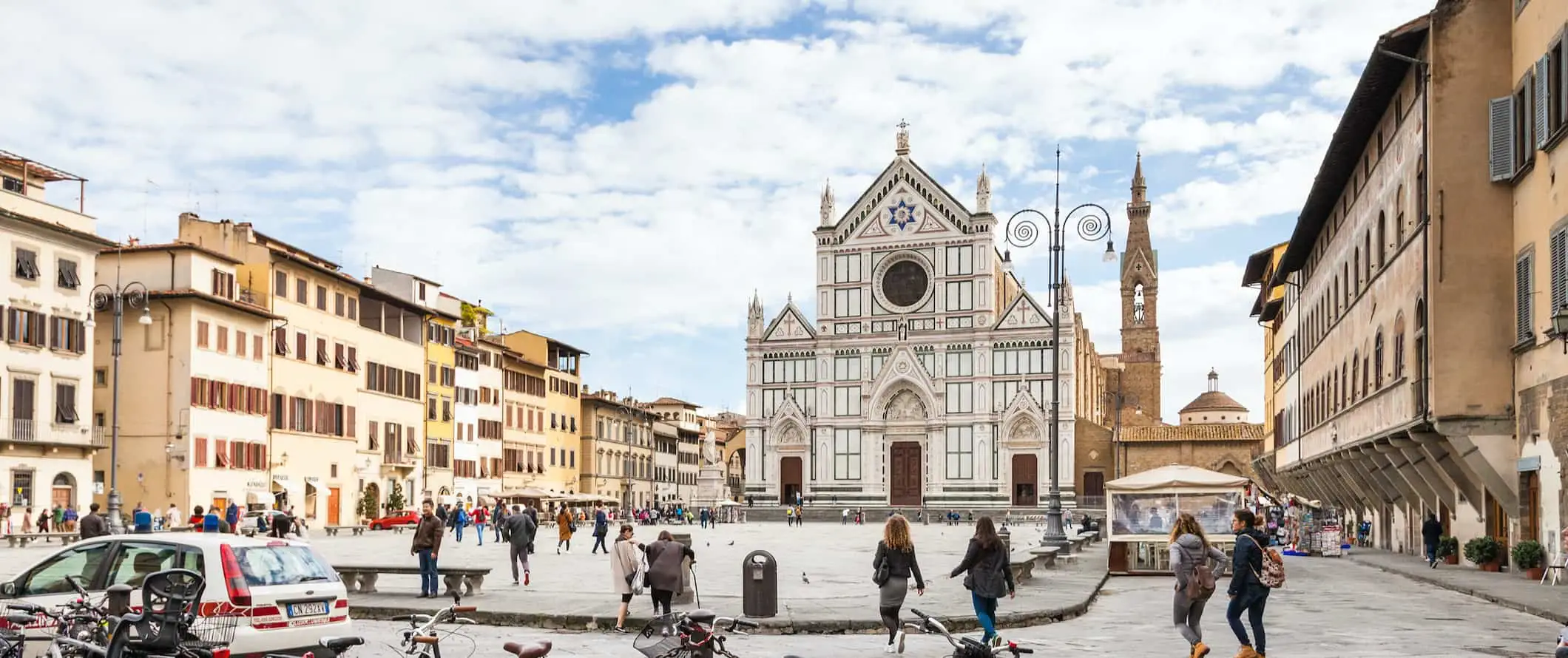 Banyak sepeda diparkir di latar depan Piazza Santa Croce di Florence, Italia