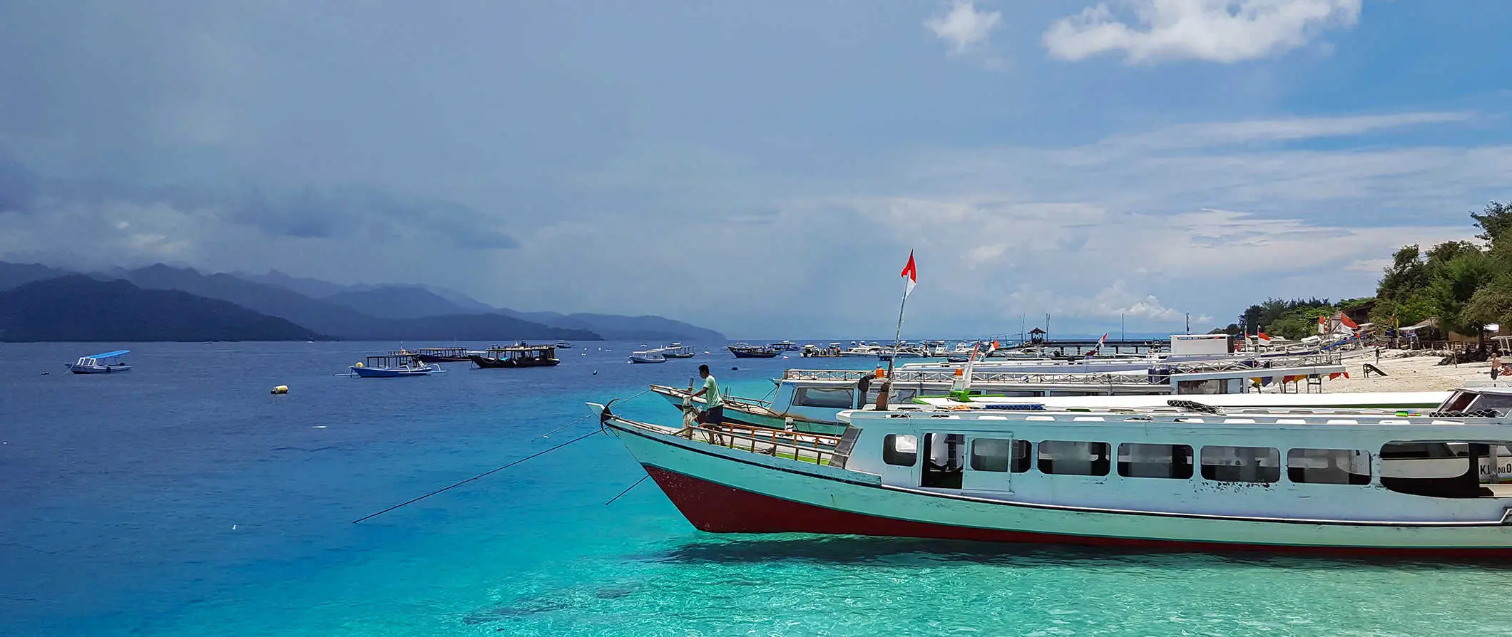 en pragtfuld strand med en båd parkeret langs kysten på Gili-øerne, Indonesien