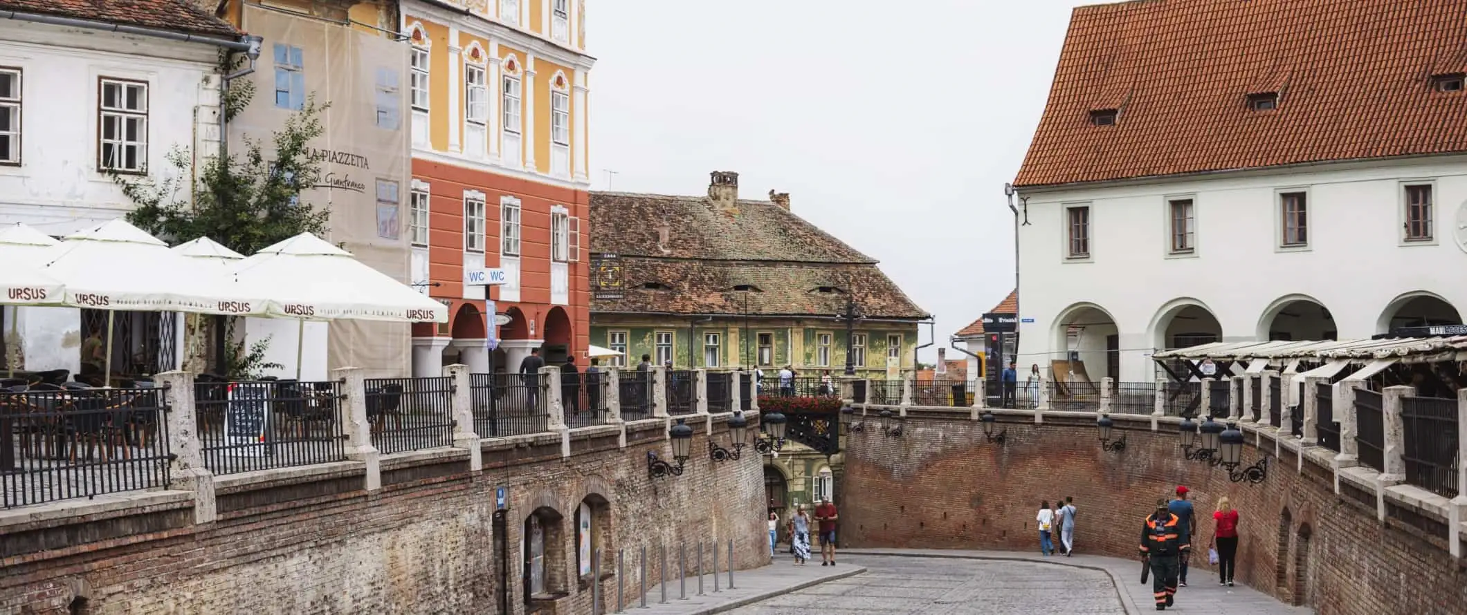 Emberek sétálnak a macskaköves utcákon Nagyszebenben, Romániában