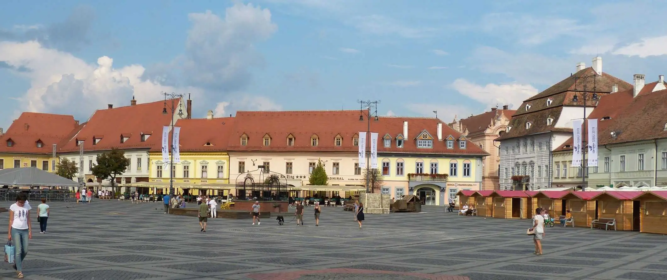 Ljudje, ki se sprehajajo po Piata Huet, glavnem trgu v zgodovinskem starem mestnem jedru v Sibiuju v Romuniji