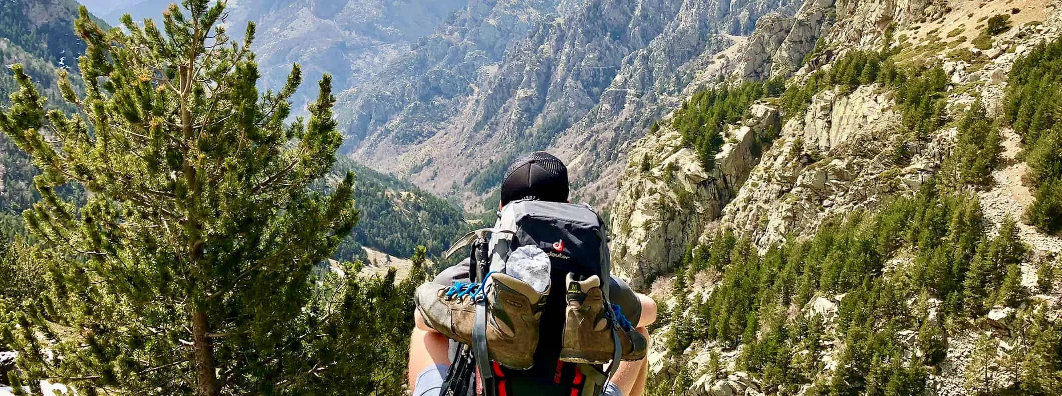 um homem usando equipamento de caminhada enquanto caminha por uma paisagem acidentada