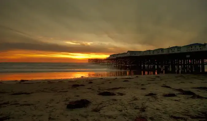 En hög träpir på San Diego-stranden under solnedgången